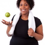 Overweight young black woman holding an apple - African people